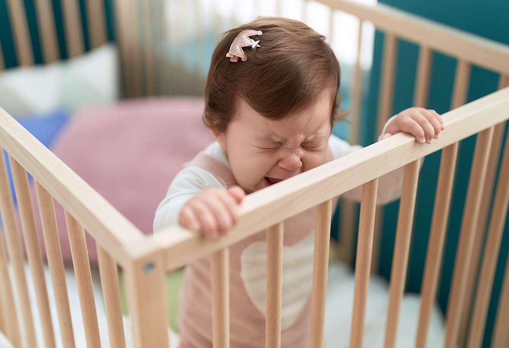 Child banging their head on the crib